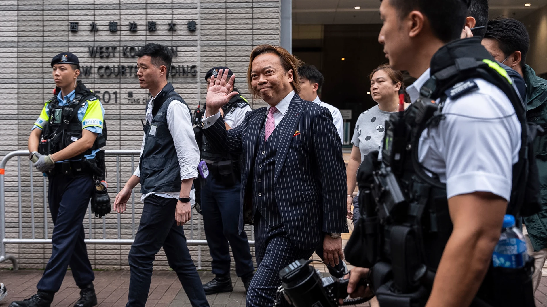 Lawrence Lau, a former pro-democracy district councilor, waves hand to media as he leaves the West Kowloon Magistrates' Courts in Hong Kong, Thursday, May 30, 2024. Fourteen pro-democracy activists were convicted in Hong Kong’s biggest national security case on Thursday by a court that said their plan to effect change through an unofficial primary election would have undermined the government’s authority and created a constitutional crisis.(AP Photo/Chan Long Hei)