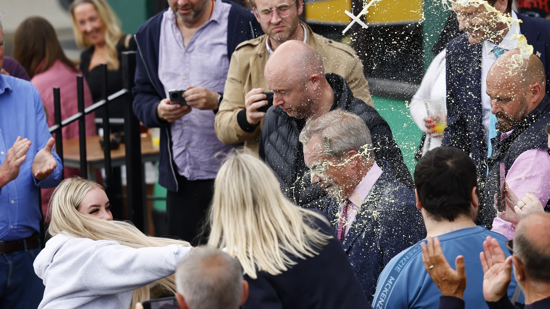 Clacton-on-sea (United Kingdom), 03/06/2024.- A young woman (L) throws a milkshake at Nigel Farage (C), leader of Reform UK party and prospective parliamentary candidate for Clacton, in Clacton-on-sea, Essex, Britain, 04 June 2024. Britain will hold a snap general election on 04 July 2024. (Reino Unido) EFE/EPA/TOLGA AKMEN