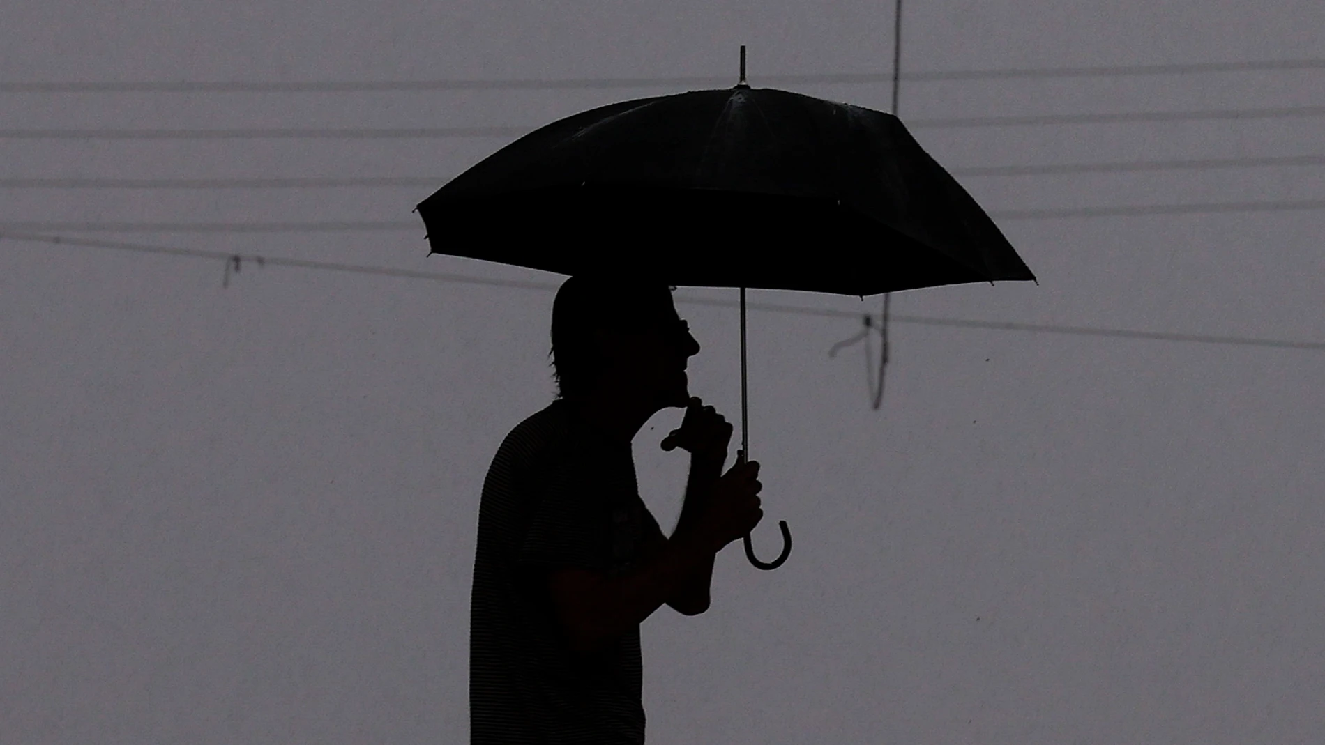 GRAFCVA1171. BURJASSOT (VALENCIA), 12/06/2024.- Una persona se protege de la lluvia con un paraguas cuando la Agencia Estatal de Meteorología (Aemet) ha elevado a naranja el aviso para la tarde de este miércoles en el interior de la provincia de Valencia por tormentas que podrían ir acompañadas de granizo. EFE/Kai Försterling