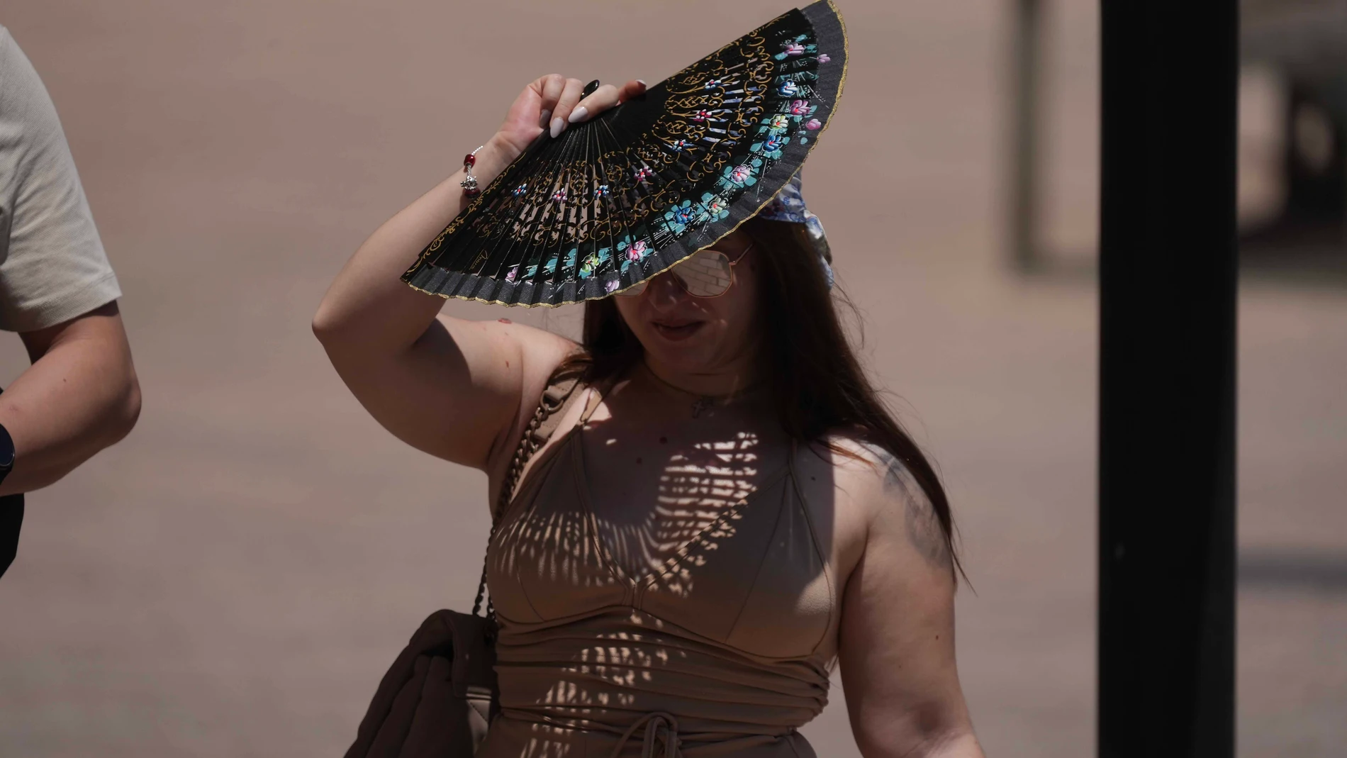 GRAFAND2289. CÓRDOBA, 04/07/2024.- Una mujer se tapa con un abanico mientras camina por Córdoba, este jueves en el que las altas temperaturas alcanzarán su pico de intensidad las próximas horas con máximas que podrían registrar 41 grados en puntos de Andalucía, con aviso naranja (riesgo importante) en las provincias de Cádiz, Córdoba, Jaén, y Sevilla por calor sofocante. EFE/Rafa Alcaide