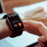 Primer plano de la mano tocando el reloj inteligente con la aplicación de salud en la pantalla. 