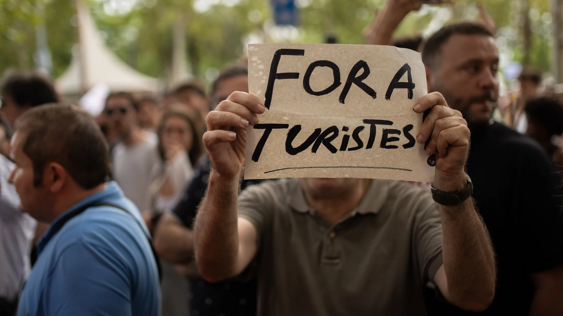 Una persona sujeta un cartel durante una manifestación contra el turismo masificado, a 6 de julio de 2024, en Barcelona, Catalunya (España). Unas 2.800 personas, según el Ayuntamiento, se han manifestado en el centro de Barcelona contra el turismo masificado, bajo el lema 'Basta. Pongamos límite al turismo'. Los manifestantes han declarado que hay una industria turística que "tiene enormes impactos negativos, laboralmente, socialmente, ambientalmente". 06 JULIO 2024;MANIFESTACIÓN;TURISMO;MAS...