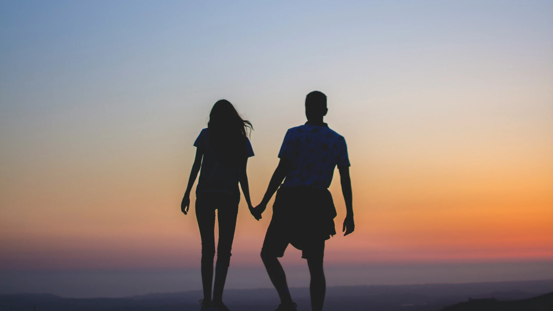 Pareja agarrada de la mano en un atardecer