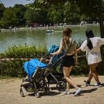 Familias con sus carritos de bebe pasean por el Retiro madrileño.