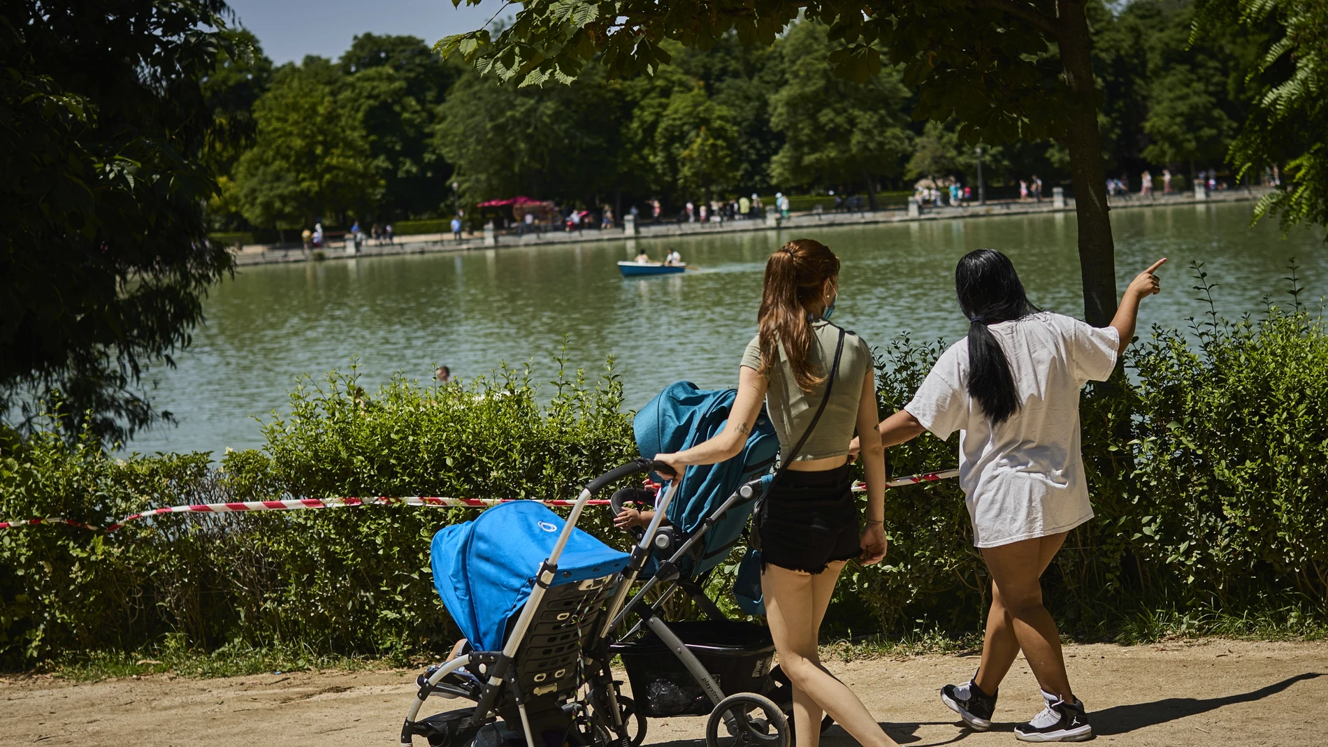 Familias con sus carritos de bebe pasean por el Retiro madrileño.