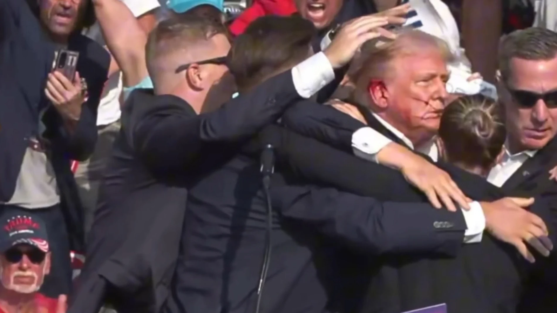 BUTLER, July 14, 2024 -- This video screenshot shows former U.S. President Donald Trump being helped off the stage at a rally in Butler, Pennsylvania of the United States after what sounded like gunshots rang out through the crowd, July 13, 2024. Video footage showed that Trump was making a speech when popping sounds rang out over the rally. Screams could be heard in the crowd, and Trump was swiftly escorted off the stage by Secret Service agents. Blood could be seen on the side of his h...