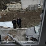 Local residents stand before a damaged house destroyed following shelling which local officials called a "Ukrainian military strike" in the town of Dokuchayevsk, in Donetsk region, Russian-controlled Ukraine, on November 29, 2024, amid the ongoing Russian-Ukrainian conflict. 