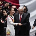 President Claudia Sheinbaum holds hands with outgoing President Andres Manuel López Obrador after taking the oath of office in the lower chamber of Congress, in Mexico City.