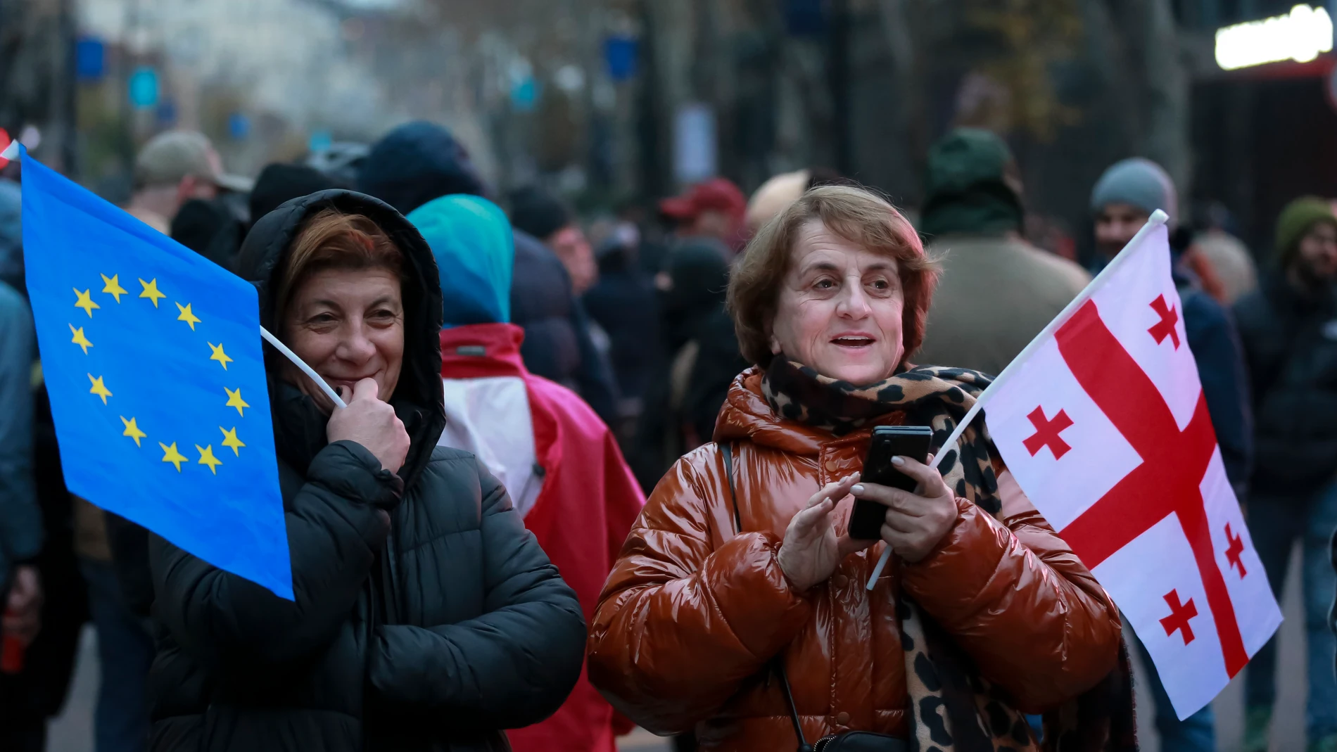 Two women hold an EU and Georgian national flag as protesters rally against the governments' decision to suspend negotiations on joining the European Union for four years, outside the parliament's building in Tbilisi, Georgia, early Sunday, Dec. 1, 2024. (AP Photo/Zurab Tsertsvadze)
