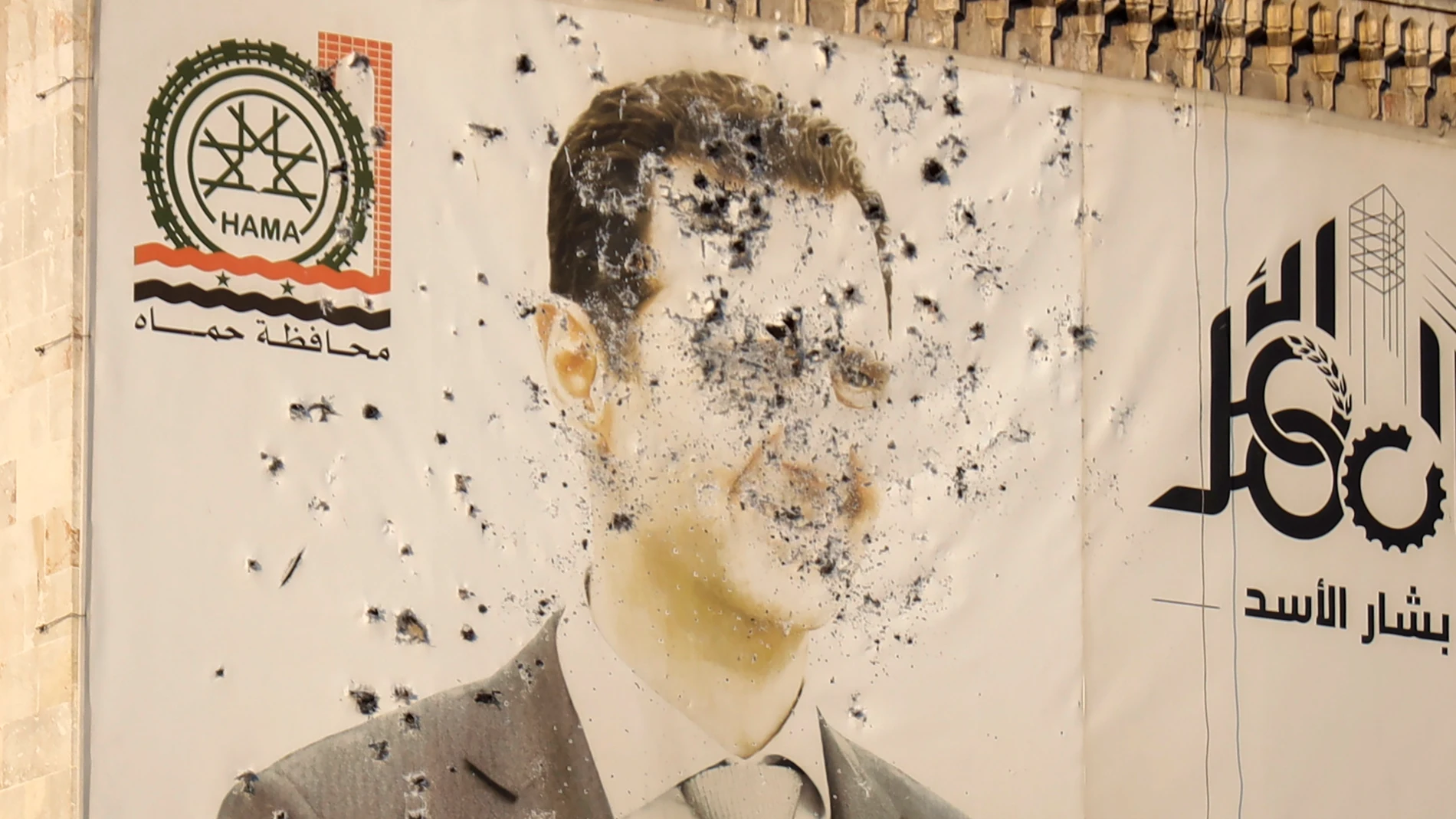 An image of Syrian President Bashar Assad, riddled with bullets, is seen on the facade of the provincial government office in the aftermath of the opposition's takeover of Hama, Syria, Friday, Dec. 6, 2024. (AP Photo/Omar Albam)