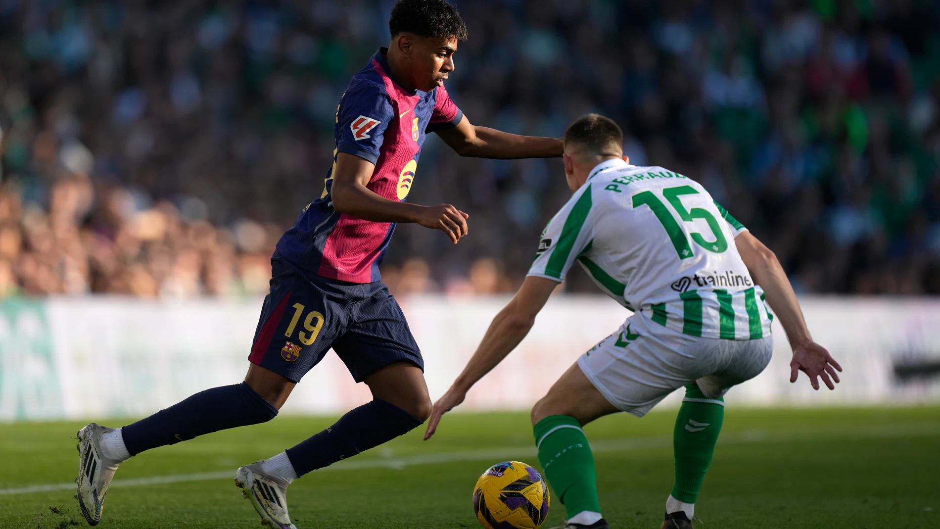 Barcelona's Lamine Yamal, left, challenges for the ball with Betis' Romain Perraud during a Spanish La Liga soccer match between Betis and Barcelona at the Benito Villamarin stadium in Seville, Spain, Saturday, Dec. 7, 2024. (AP Photo/Jose Breton)