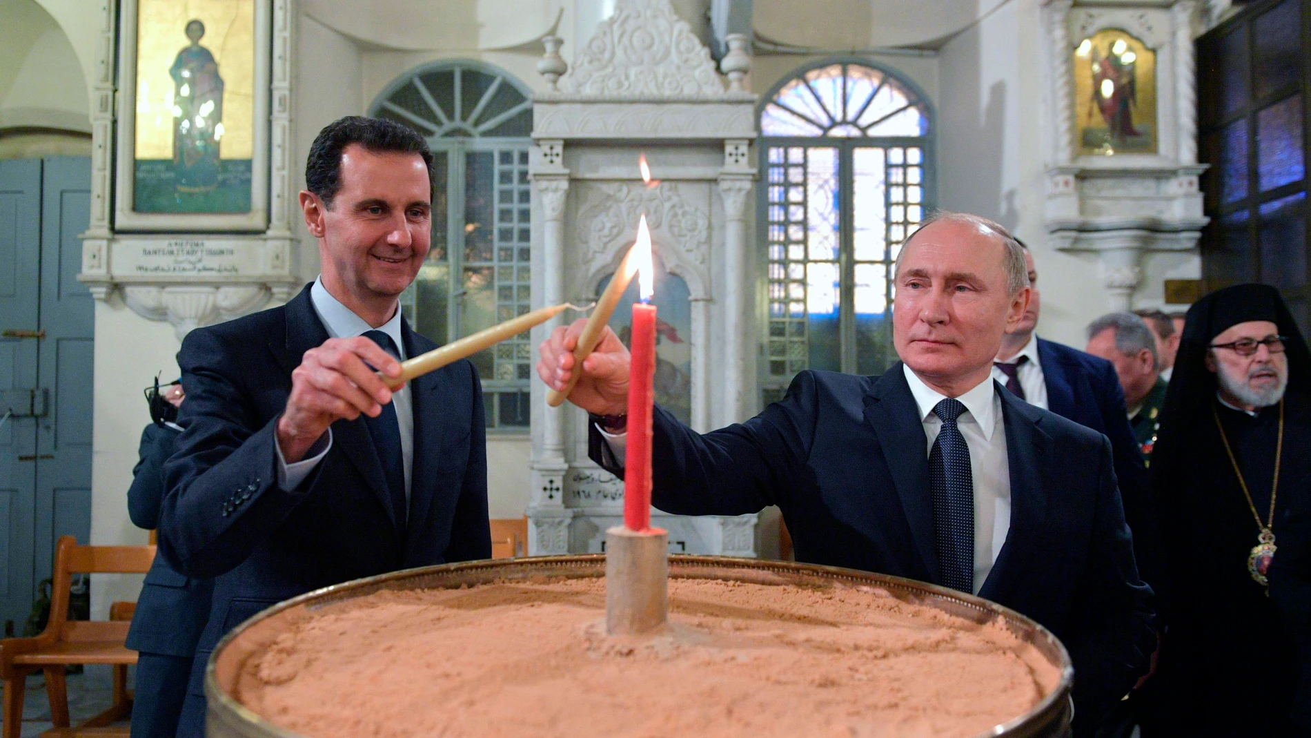 FILE - Russian President Vladimir Putin, right, and Syrian President Bashar Assad light candles while visiting an orthodox cathedral for Christmas, in Damascus, Syria, Jan. 7, 2020. (Alexei Druzhinin, Sputnik, Kremlin Pool Photo via AP, File)