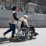 Una mujer mayor en silla de ruedas y su cuidadora pasean por el centro de la ciudad
