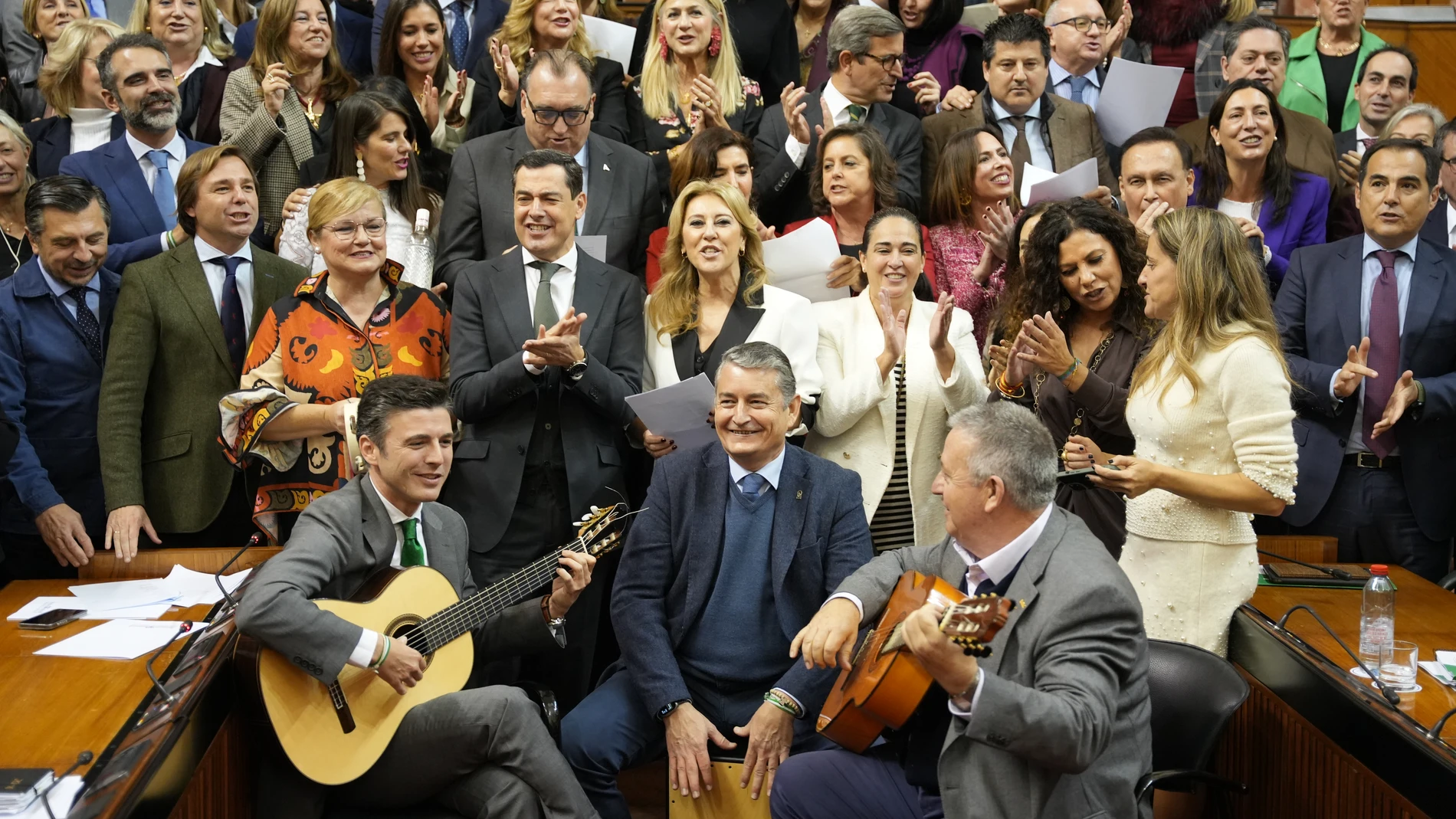 El presidente de la Junta de Andalucía, Juanma Moreno (c), junto al grupo parlamentario del PP-A, y trabajadores del Parlamento Andaluz, cantan un villancico tras la sesión plenaria donde se ha aprobado el proyecto de Ley de Presupuestos de la Comunidad Autónoma de Andalucía para 2025. A 19 de diciembre de 2024, en Sevilla (Andalucía, España). PP-A aprueba en solitario el Presupuesto andaluz para 2025 incorporando medio centenar de enmiendas de la oposición. 19 DICIEMBRE 2024 María José Lóp...