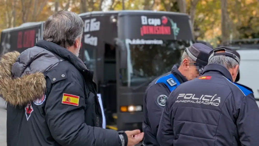 Agentes de la Policía Municipal, junto al presidente de Hazte Oír, Ignacio Arsuaga, y, de fondo, el autobús con el que piden la dimisión de Pedro Sánchez