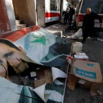 Rebeldes retiran un pancarta del depuesto presidente Bachar al Asad en Damasco