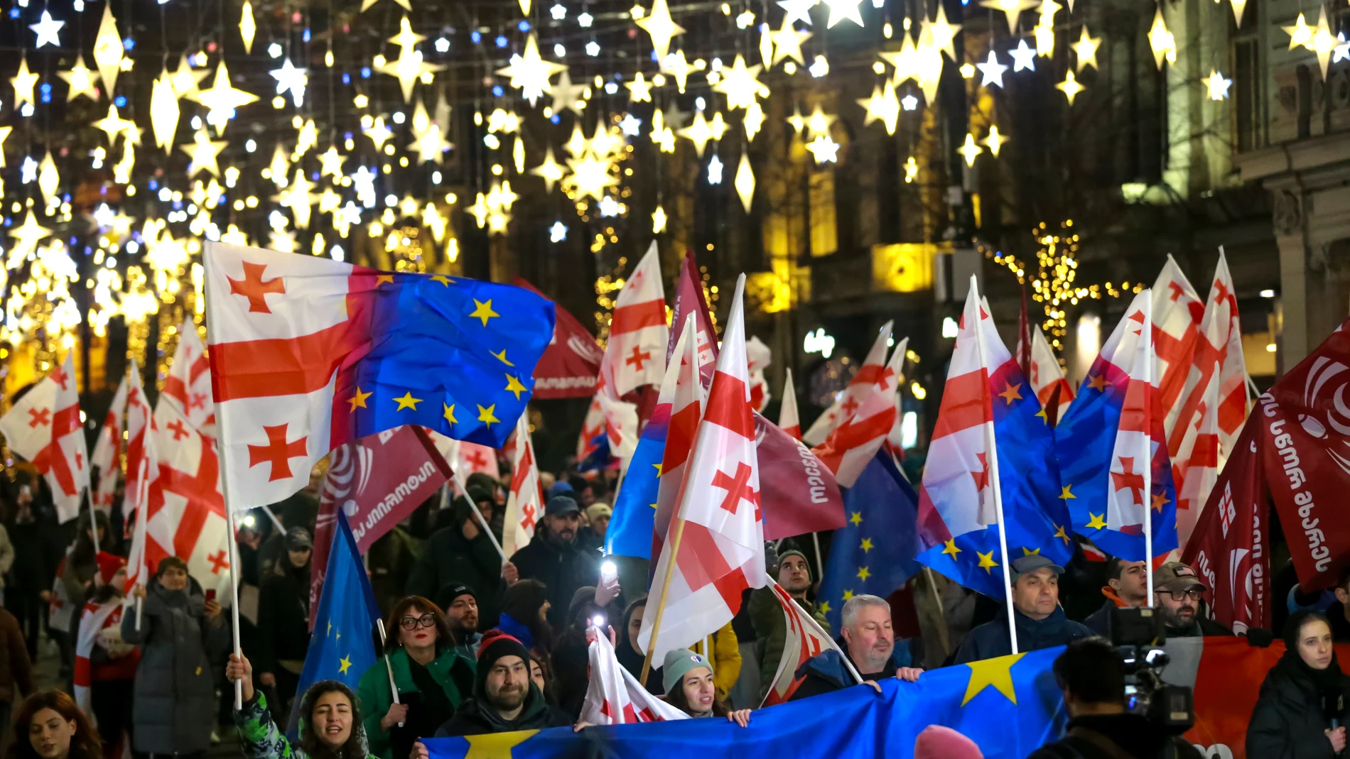 Demonstrators with Georgian national and EU flags march during an anti-government rally outside the Parliament building in Tbilisi, Georgia, on Saturday, Dec. 28, 2024. (AP Photo/Zurab Tsertsvadze)