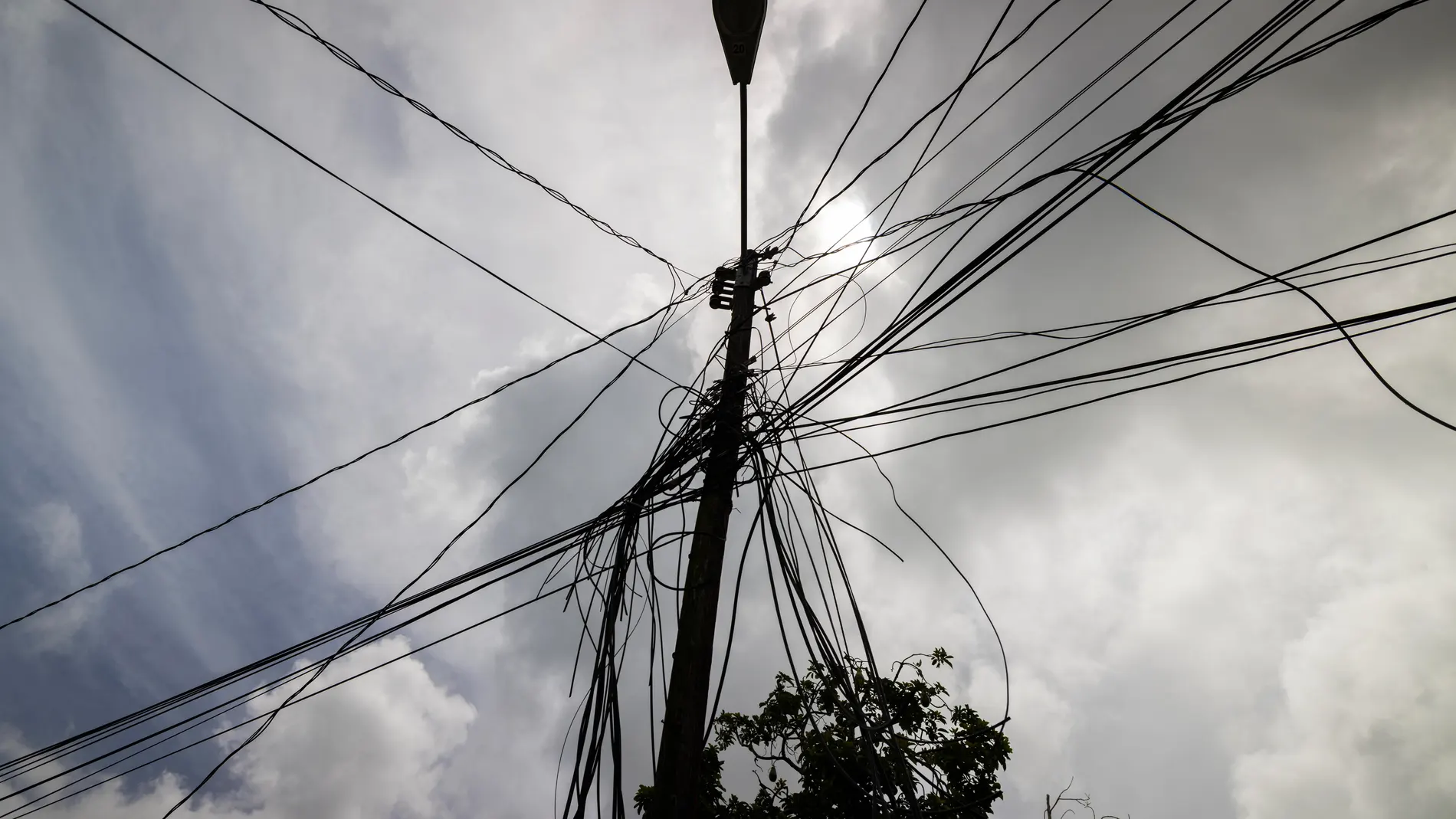 FILE - A utility pole with loose cables towers over a home in Loiza, Puerto Rico, Sept. 15, 2022. (AP Photo/Alejandro Granadillo, File)