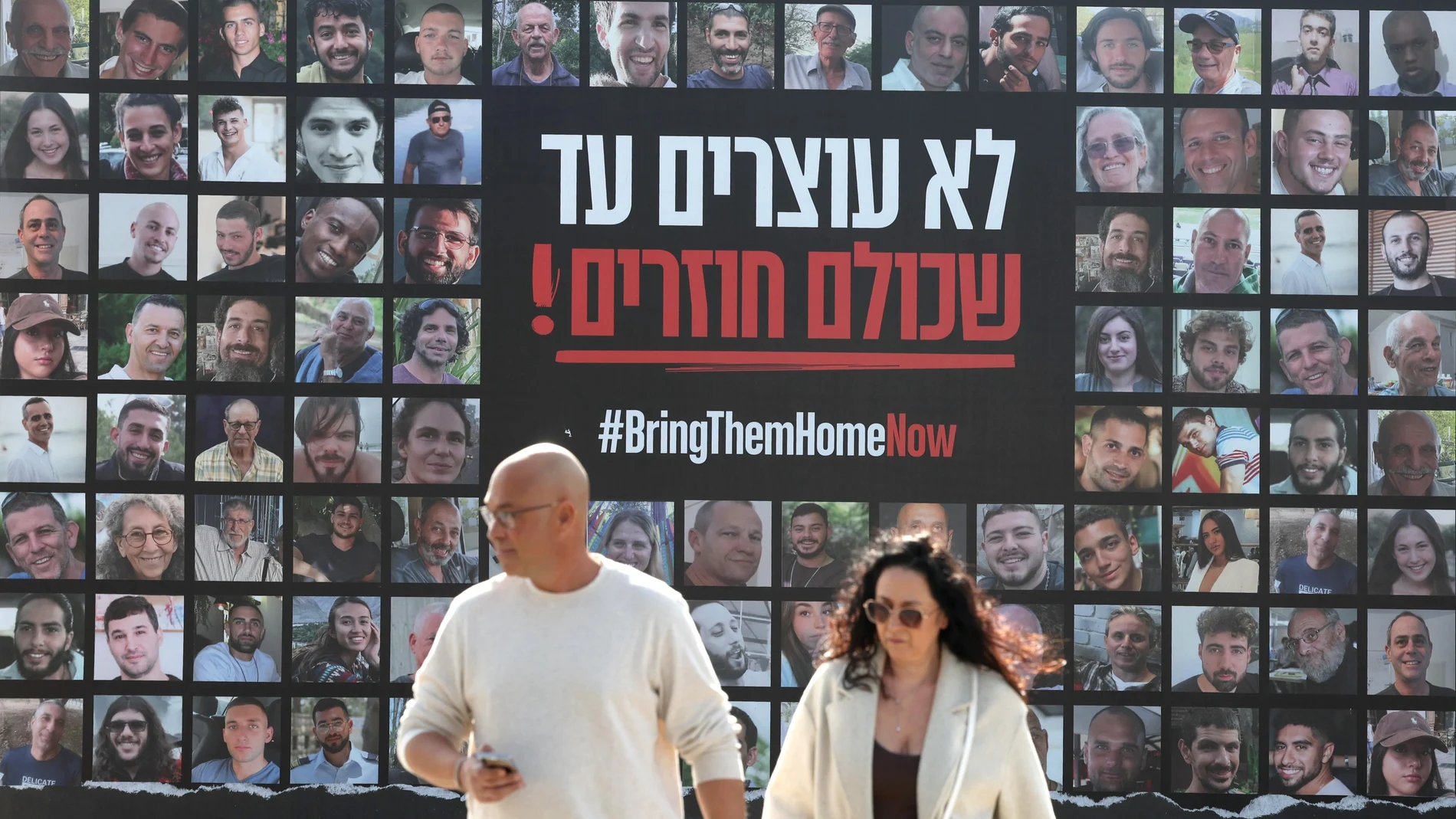People walk past a billboard showing images of Israeli hostages held by Hamas in Gaza reading 'Don't stop until everyone is back', in Jerusalem, 15 January 2025. According to Israel's military, around 100 Israeli hostages remain in captivity in the Gaza Strip, including the bodies of 33 confirmed dead. More than 46,500 Palestinians and over 1,400 Israelis have been killed, according to the Palestinian Health Ministry and the Israeli Army, since Hamas militants launched an attack against Israel from the Gaza Strip on 07 October 2023, and the Israeli operations in Gaza and the West Bank which followed it.