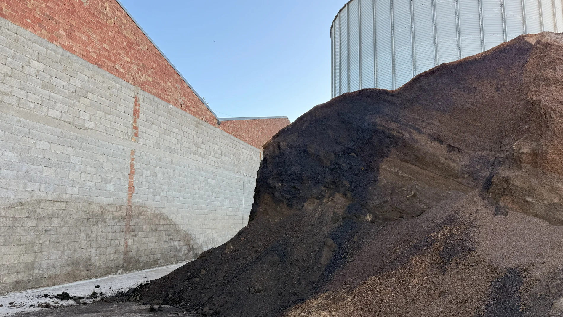 En la montaña de arroz inservible hay partes que se han quedado solidificadas y ahora necesitan romperlas con una máquina antes de que se las puedan llevar