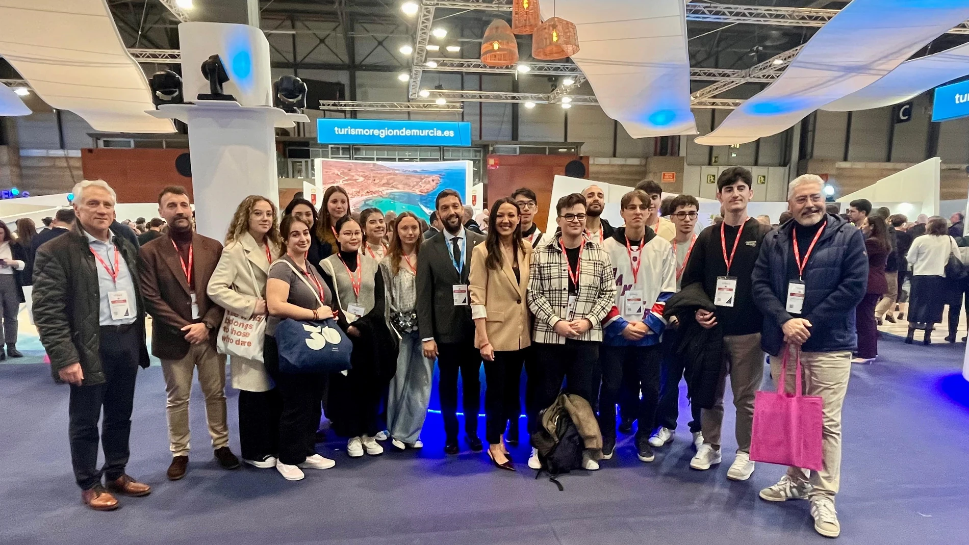 La consejera Carmen Conesa y el director del Instituto de Turismo, con un grupo de estudiantes de Turismo ante el estand de la Región en Fitur
