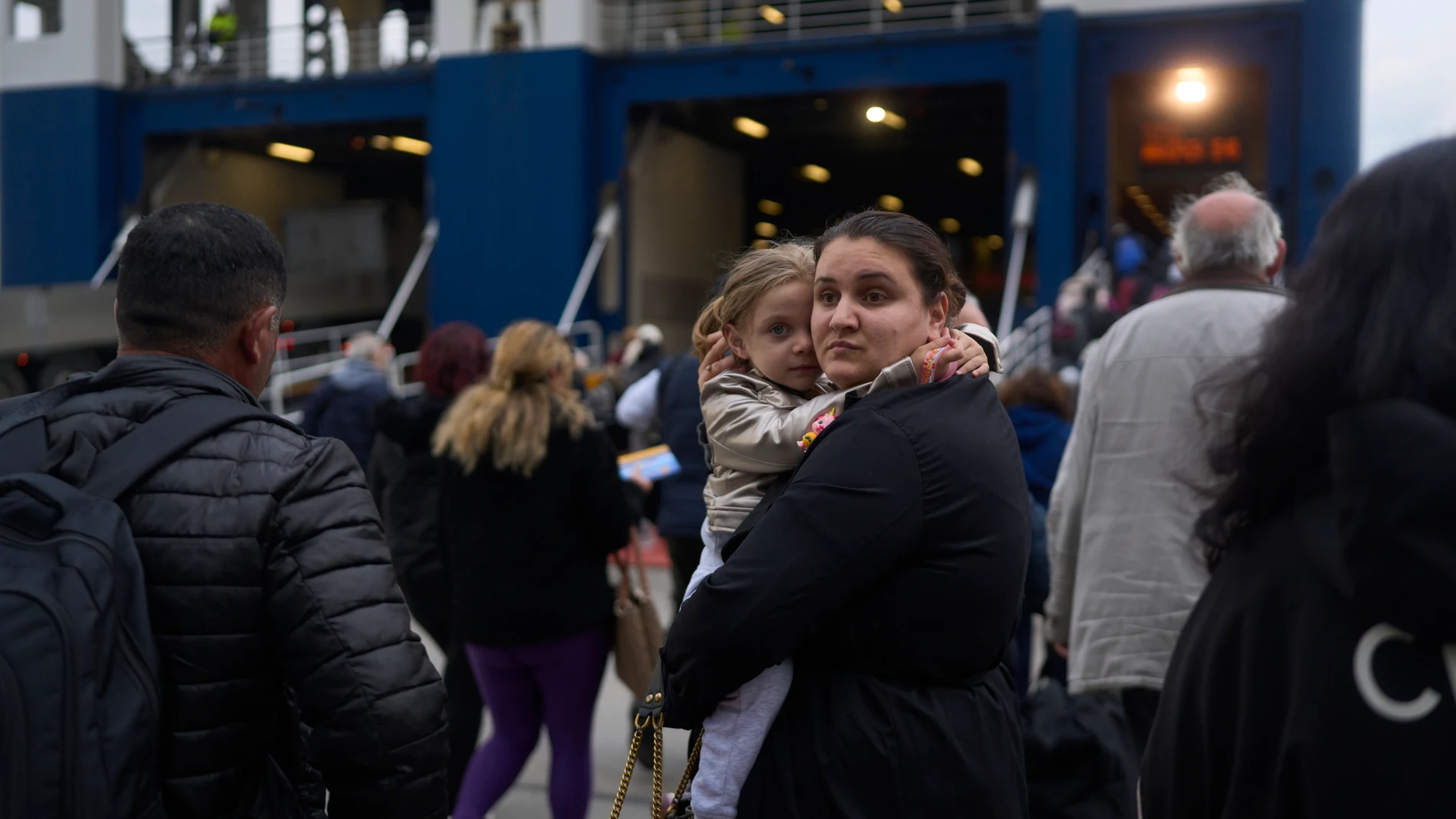 A woman with her child prepare to board a ferry bound for the Greek mainland, in the earthquake-struck island of Santorini, Greece, Tuesday, Feb. 4, 2025. (AP Photo/Petros Giannakouris)