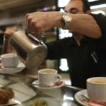 Un camarero sirviendo varios cafés en la barra de un bar