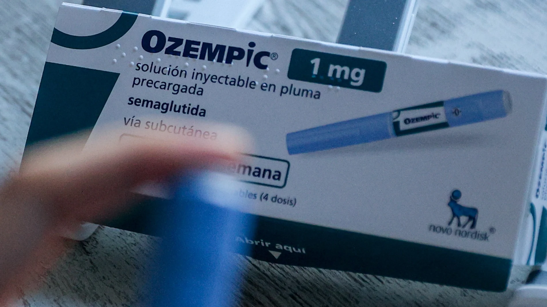 Foto de un envase de Ozempic sobre una mesa blanca con una inyección en primer plano desenfocada