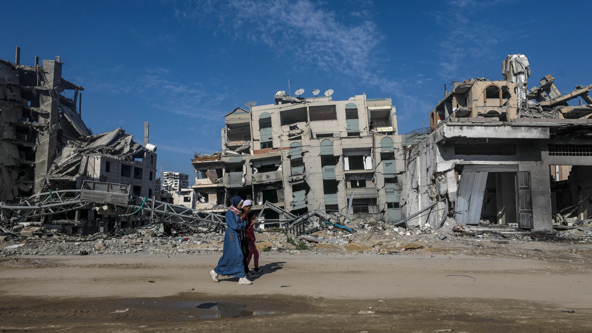 GAZA (-), 15/02/2025.- Palestinians walk next to destroyed buildings in Al Remal neighborhood of Gaza City, 14 February 2025 (issued 15 February 2025). Israel and Hamas implemented the first phase of a hostage release and ceasefire deal on 19 January 2025. More than 48,000 Palestinians have been killed in the Gaza Strip, according to the Palestinian Ministry of Health, since Israel launched a military campaign in the strip in response to a cross-border attack led by the Palestinian militant g...