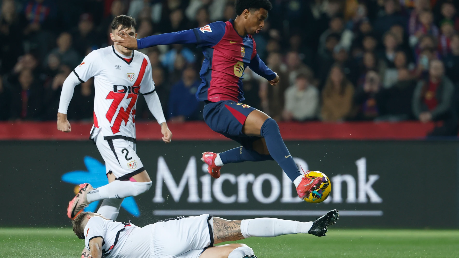 Rayo's Florian Lejeune, bottom, challenges for the ball with Barcelona's Alejandro Balde during a Spanish La Liga soccer match between Barcelona and Rayo Vallecano at the Lluis Companys Olympic Stadium in Barcelona, Spain, Monday, Feb. 17, 2025. (AP Photo/Joan Monfort)