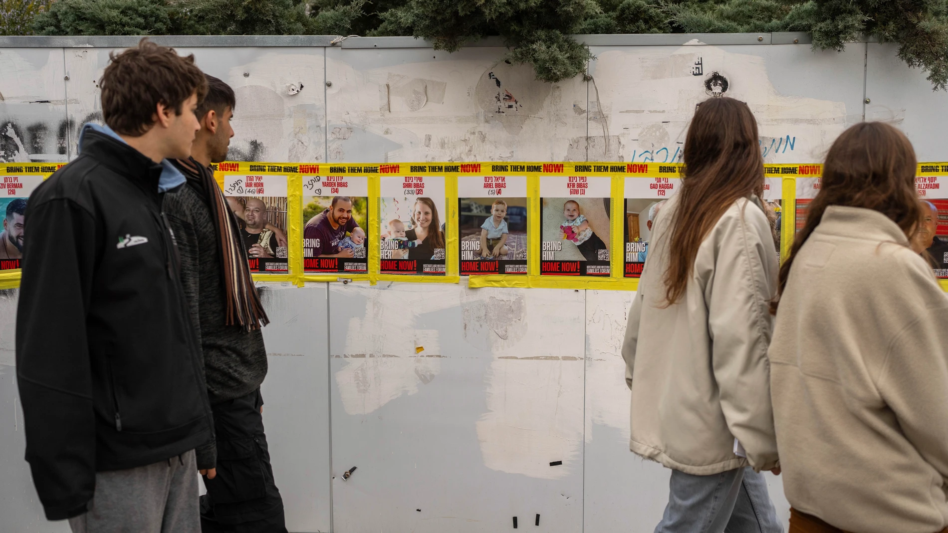 Teenagers walk by photos of the Biebs family and other hostages taken captive by Hamas militants on Oct. 7, 2023, in Jerusalem, Wednesday, Feb. 19, 2025. (AP Photo/Ohad Zwigenberg)