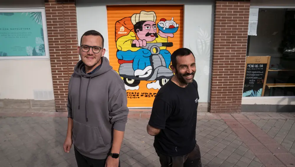Propietario de L'Artigiano junto al artista que ha pintado su cierre en una campaña de Just Eat. David Jar