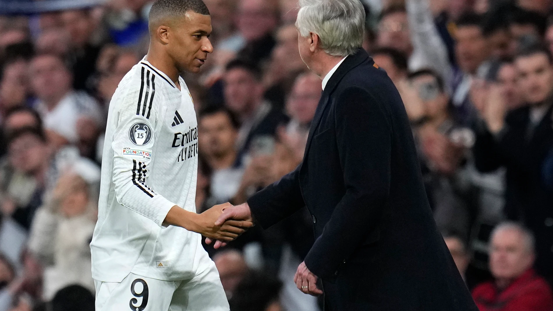 Real Madrid's head coach Carlo Ancelotti shake hands with Real Madrid's Kylian Mbappe during the Champions League playoff second leg soccer match between Real Madrid and Manchester City at the Santiago Bernabeu Stadium in Madrid, Spain, Wednesday, Feb. 19, 2025. (AP Photo/Manu Fernandez)