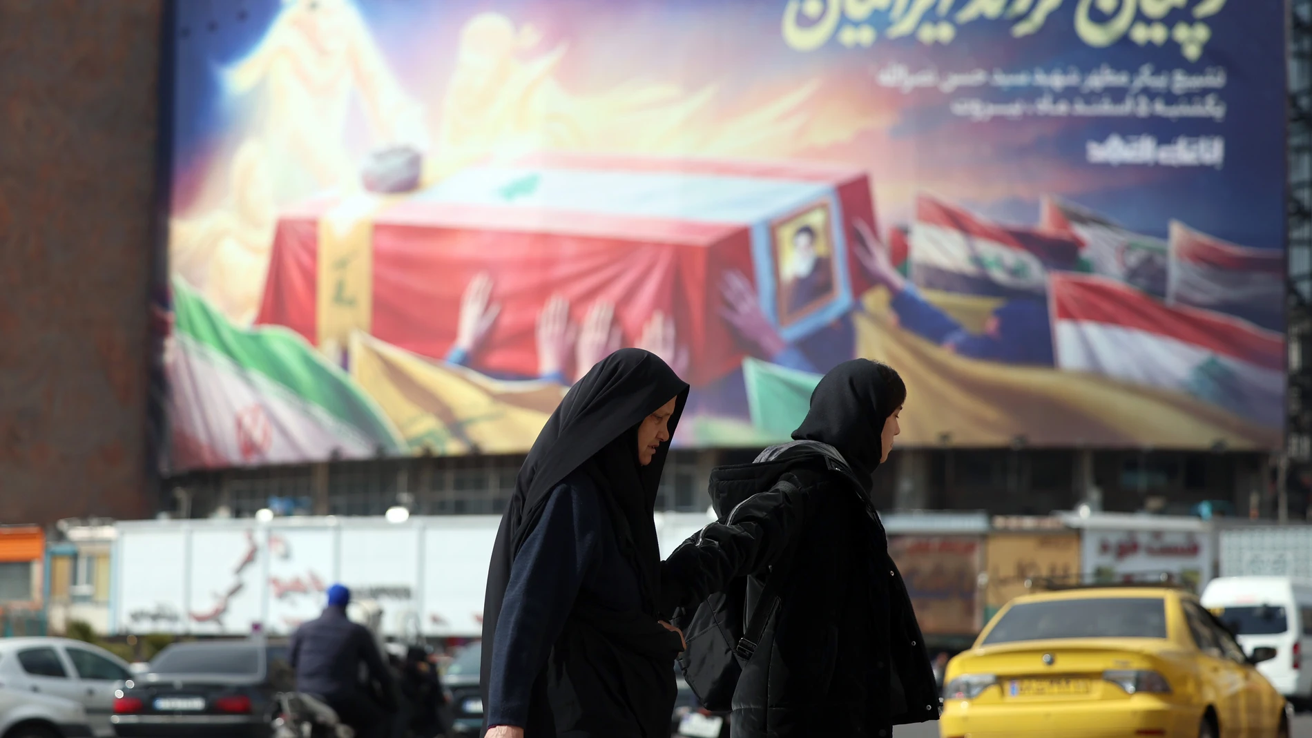 TEHRAN (IRAN(Islamic Republic Of)), 20/02/2025.- Iranian women walk past a banner with late Hezbollah leader Hassan Nasrallah coffin with a sentence reading in Persian 'Iranians keep their promises' at the Valiasr square a head of Nasrallah funeral, in Tehran, Iran, 20 February 2025.The funeral of Hezbollah late leader Hassan Nasrallah will be held on 23 February in Beirut, Lebanon, five months after he was killed in an Israeli air attack in Lebanon's capital, according to the Lebanese group....