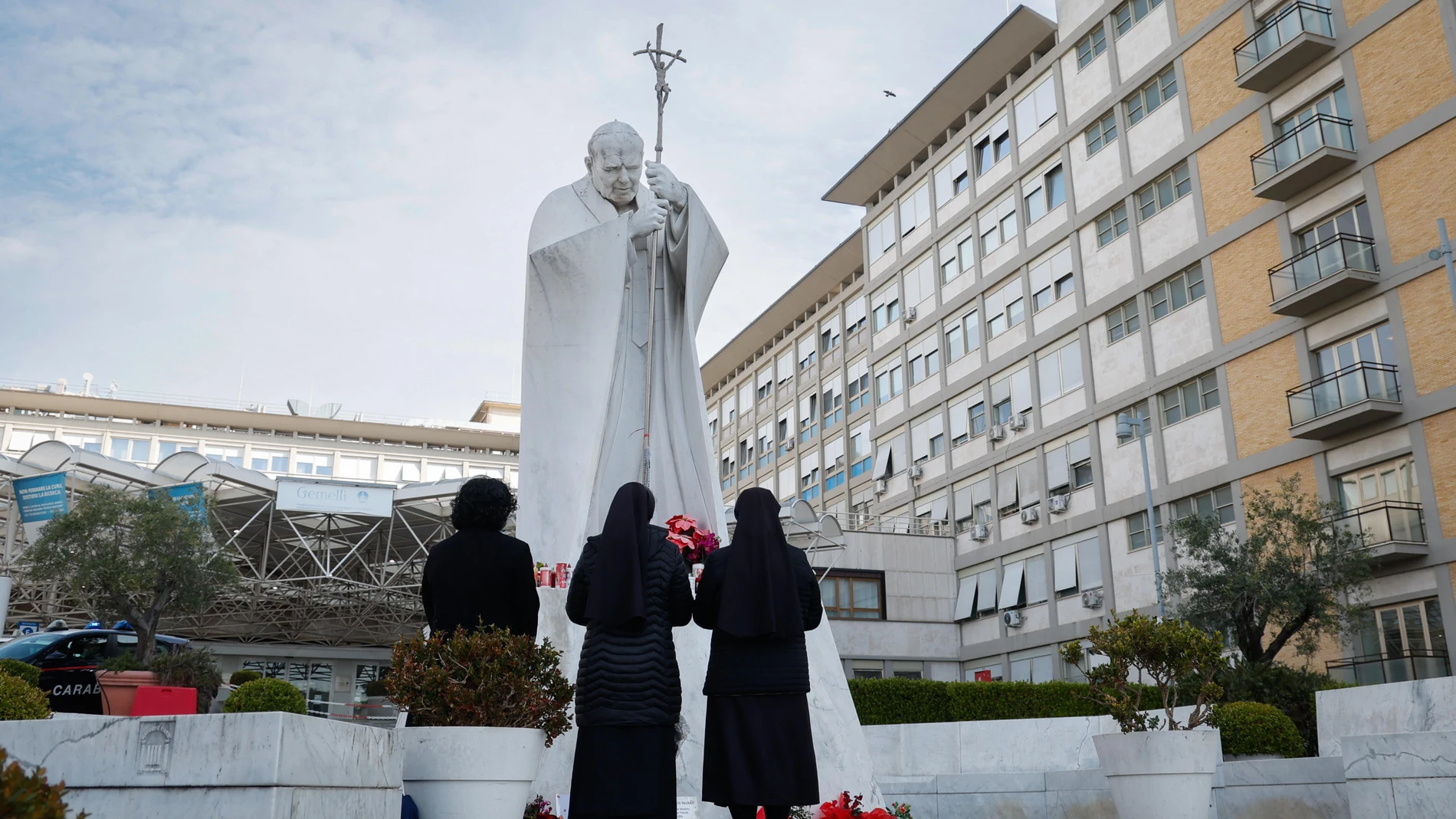 ROME (Italy), 23/02/2025.- Nuns pray before the statue of late Pope John Paul II outside the Agostino Gemelli Hospital where Pope Francis is currently hospitalized, in Rome, Italy, 23 February 2025. The pope continues his treatments for bilateral pneumonia after being admitted to hospital on 14 February due to a respiratory tract infection. (Papa, Italia, Roma) EFE/EPA/GIUSEPPE LAMI