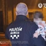 Un agente de la Policía Local de Murcia traslada al exterior a uno de los menores