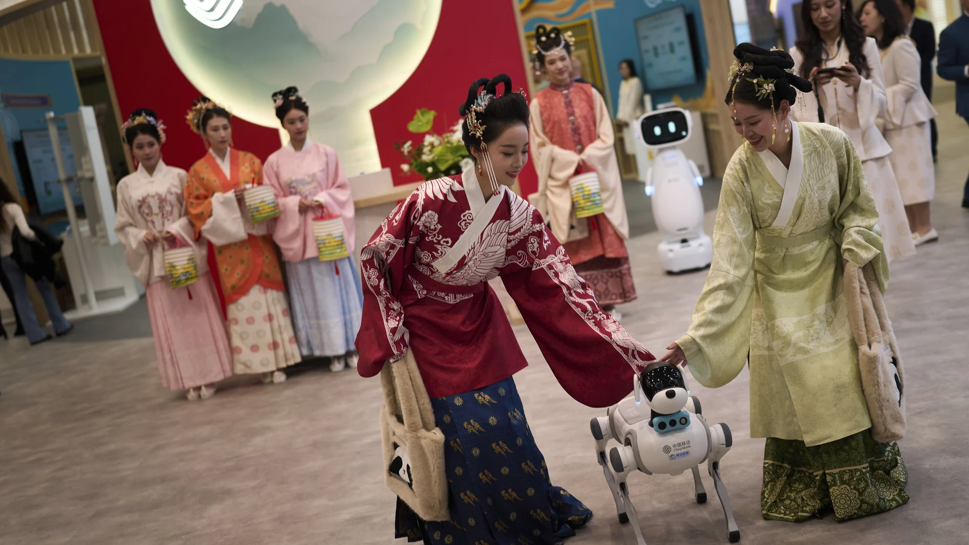 A dog-shaped robot manufactured by China Mobile Home Service Robots stands next to representatives of the company, during its presentation at the Mobile World Congress in Barcelona, Spain, Monday, March 3, 2025. (AP Photo/Emilio Morenatti)