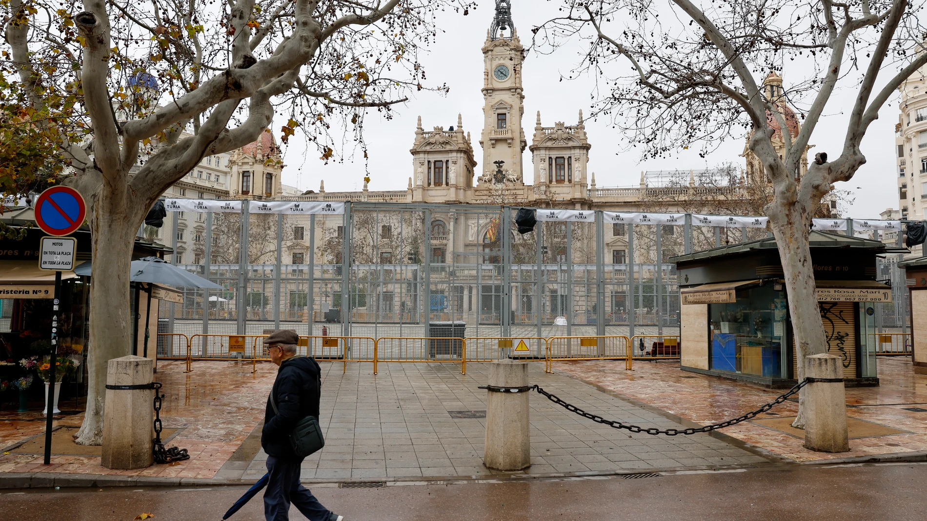 GRAFCVA6023. VALENCIA, 06/03/2025.- Una persona pasa junto al recinto de la mascletà en la plaza del ayuntamiento que se mantiene suspendida durante este jueves ante la alerta meteorológica naranja en la ciudad de València. EFE/Ana Escobar