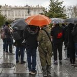 Un grupo de turistas se protegen de la lluvia con sus paraguas en el centro de Madrid. 
