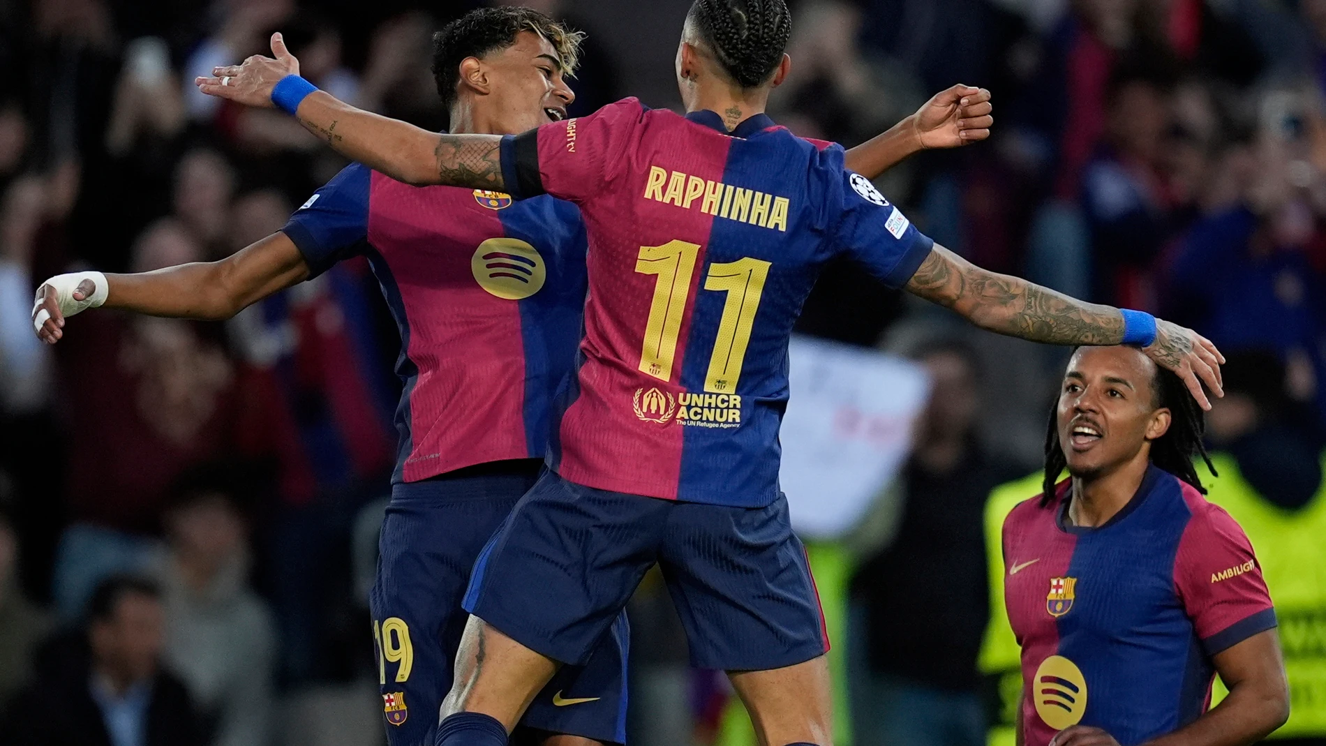 Barcelona's Raphinha, center, celebrates with Barcelona's Lamine Yamal, left, after scoring his side's opening goal during the Champions League round of 16 second leg soccer match between FC Barcelona and SL Benfica at the Lluis Companys Olympic Stadium in Barcelona, Spain, Tuesday, March 11, 2025. (AP Photo/Emilio Morenatti)