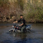 Un refugiado alauí cruza la frontera entre Siria y Líbano a través de río Al-Nahr al-Kabir en su moto