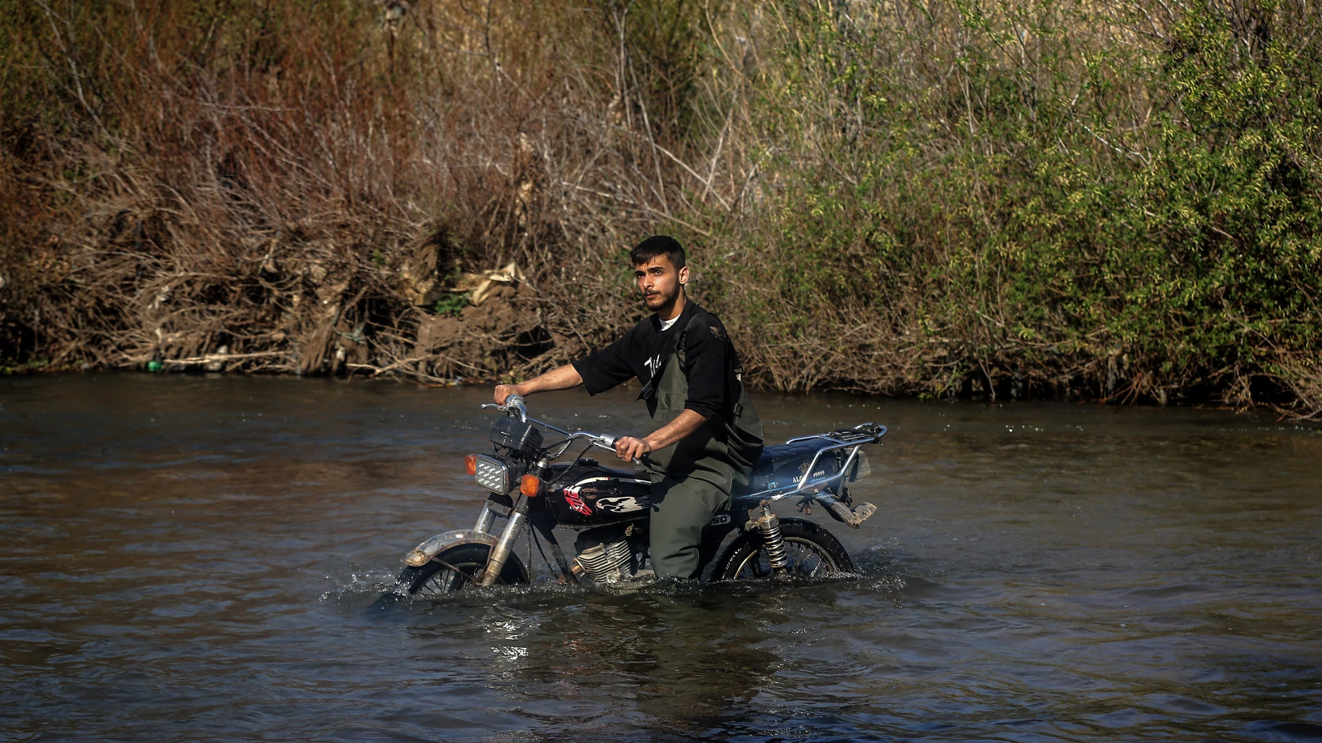 11 March 2025, Lebanon, Hekr El Dahri: A Syrian Alawite refugee crosses the al-Nahr al-Kabir river with his motorbike into the Lebanese village of Hekr El Dahri, fleeing violence in the Syrian coastal provinces of Latakia and Tartus. Thousands of Syrians, mainly Alawites, have crossed into Lebanon from areas considered strongholds of Syria's ousted former President Bashar al-Assad, after hundreds of civilians were killed in the fighting between government forces and insurgents loyal to the de...