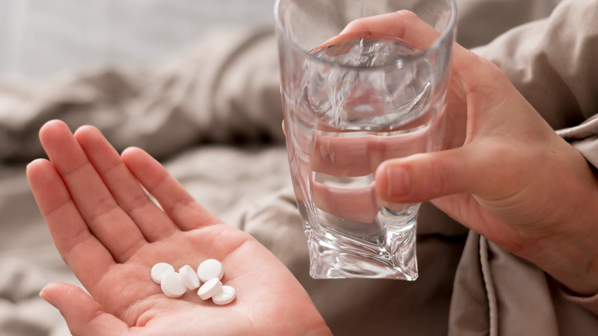 Un puñado de aspirinas pastillas con vaso de agua