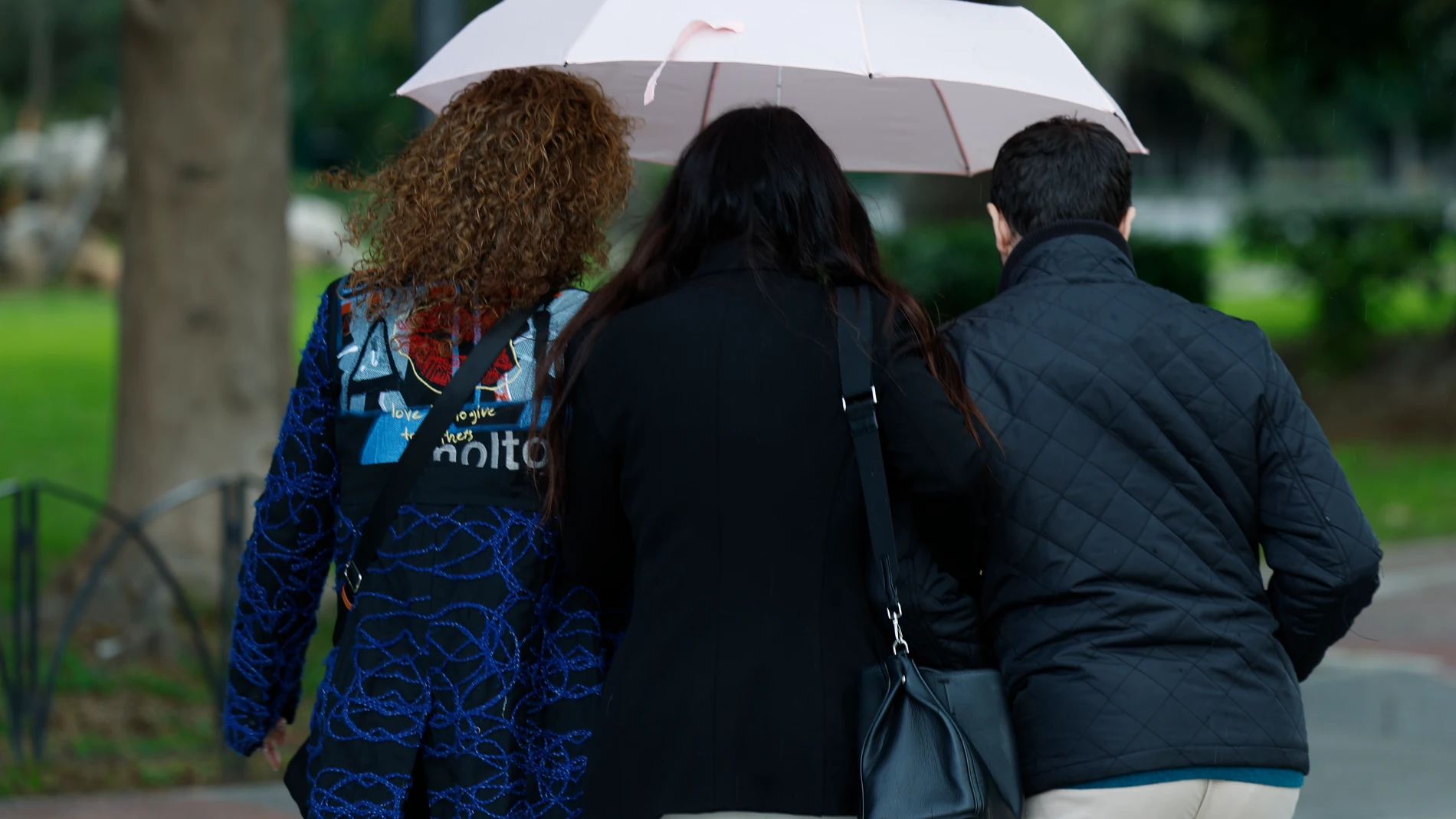GRAFAND7345. MÁLAGA, 25/03/2025.-Tres personas se resguardan debajo de un paraguas este miércoles en Málaga en el que la lluvia ha regresado después de una breve tregua. EFE/ Jorge Zapata