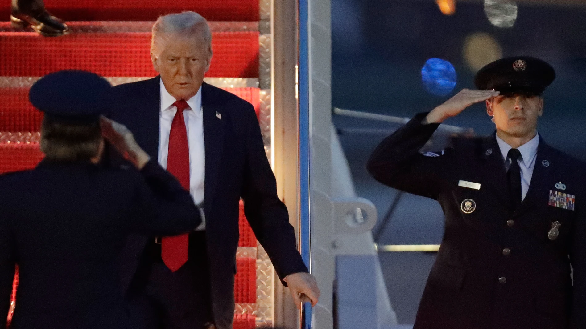 President Donald Trump, center, is greeted by Air Force Col. Angela F. Ochoa, Commander, 89th Airlift Wing, left, as he walks down the stairs of Air Force One upon his arrival at Joint Base Andrews, Md., Sunday, March 30, 2025. (AP Photo/Luis M. Alvarez)