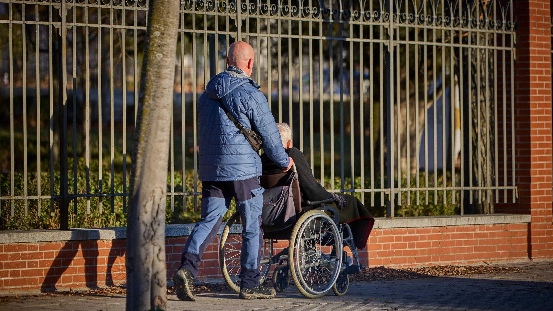 Una persona lleva a otra en silla de ruedas