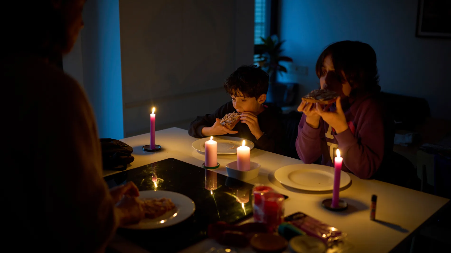 A family eats a snack by candlelight during a blackout in Barcelona, Spain, Monday, April 28, 2025. (AP Photo/Emilio Morenatti)