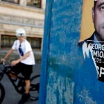 Un ciclista pasa junto a un cartel electoral del candidato ultranacionalista George Simion en Bucarest