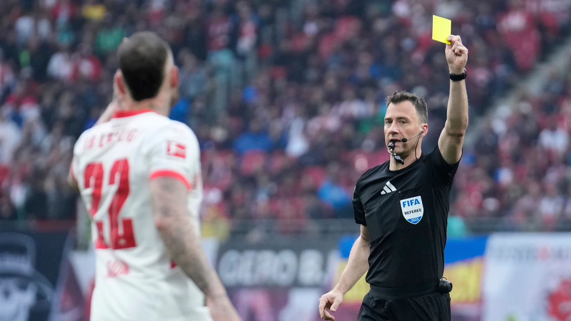 Referee Felix Zwayer shows a yellow card to Leipzig's David Raum during the German Bundesliga soccer match between RB Leipzig and FC Bayern Munich at the Red Bull Arena in Leipzig, Germany, Saturday, May 3, 2025. (AP Photo/Ebrahim Noroozi)