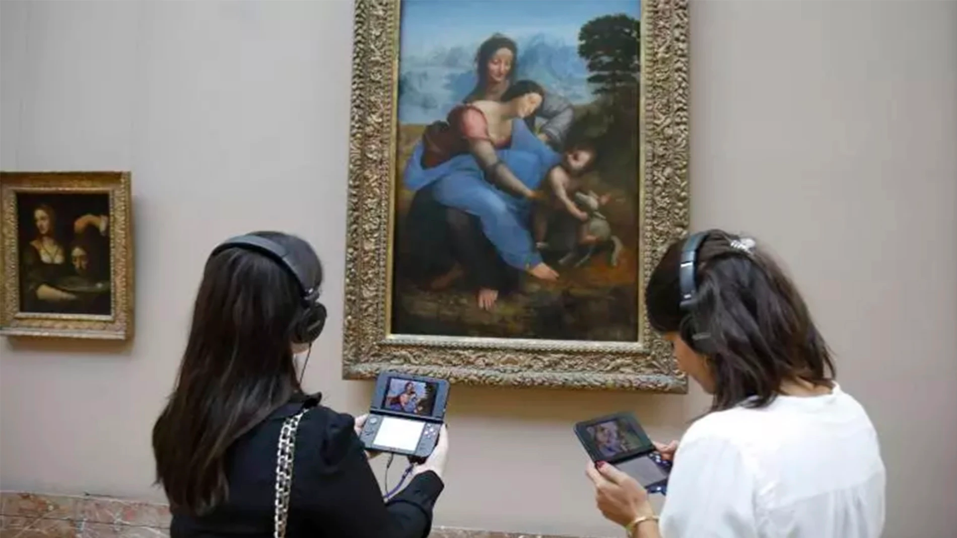 Dos visitantes obteniendo información sobre 'La Virgen, el Niño Jesús y Santa Ana' (da Vinci) con una 3DS